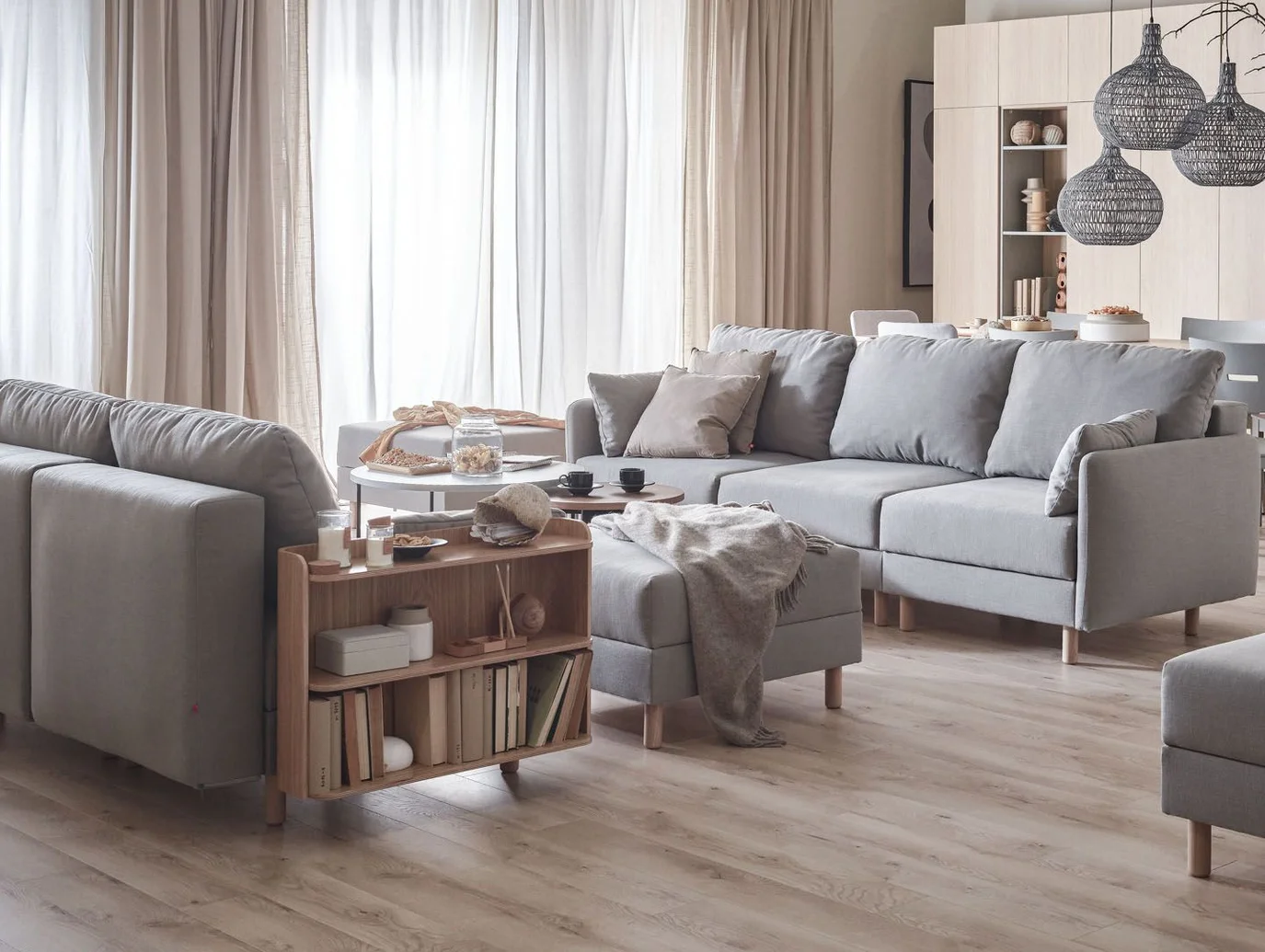 jasny salon z szarą sofą i meblami z jasnego drewna